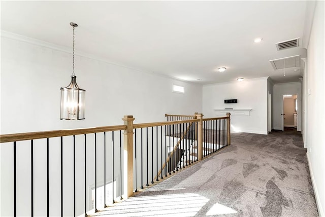 corridor with carpet floors, visible vents, attic access, ornamental molding, and baseboards