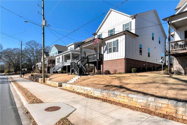 view of front facade with board and batten siding, a residential view, brick siding, and stairway