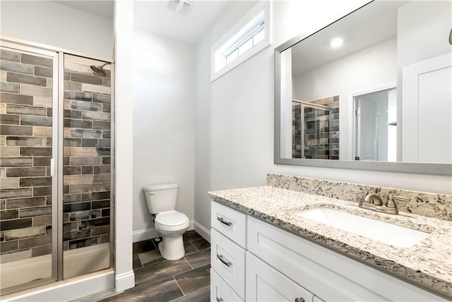 bathroom featuring toilet, a stall shower, vanity, and baseboards