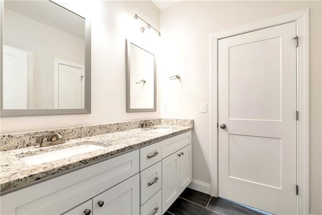 bathroom with a sink, baseboards, and double vanity