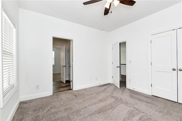 unfurnished bedroom featuring baseboards, multiple windows, and light colored carpet