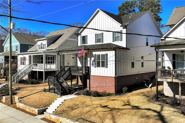 view of front facade featuring board and batten siding, a sunroom, a shingled roof, and stairway