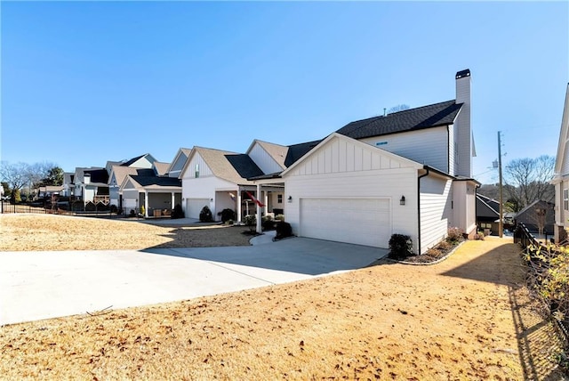 view of front of property with board and batten siding, concrete driveway, a chimney, and a garage