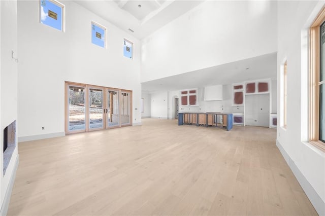 unfurnished living room featuring light wood-type flooring and a high ceiling