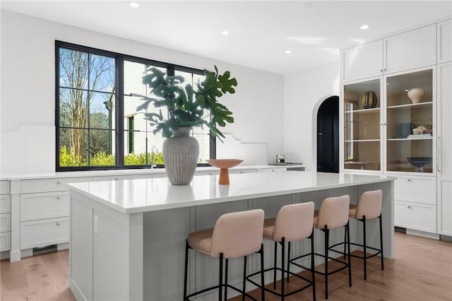 kitchen with a spacious island, white cabinets, a breakfast bar area, and light wood-type flooring