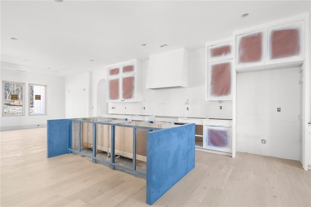 kitchen featuring light wood-type flooring, premium range hood, white cabinets, and a center island