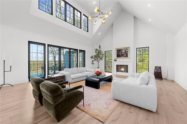 living room featuring a chandelier, light hardwood / wood-style flooring, and a towering ceiling