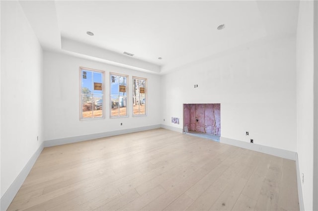 unfurnished living room featuring light hardwood / wood-style floors and a tray ceiling