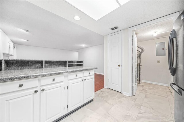23 Chelsea Ct, Avondale Estates, GA 30002 - kitchen with marble finish floor, white cabinets, baseboards, visible vents, and freestanding refrigerator