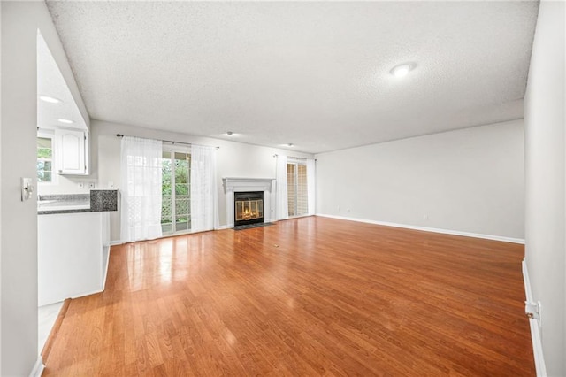 23 Chelsea Ct, Avondale Estates, GA 30002 - unfurnished living room featuring a fireplace with flush hearth, baseboards, a textured ceiling, and light wood finished floors