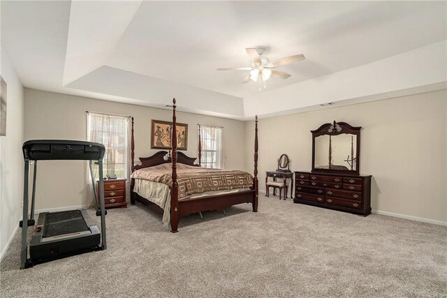 bedroom with light carpet, a tray ceiling, and ceiling fan