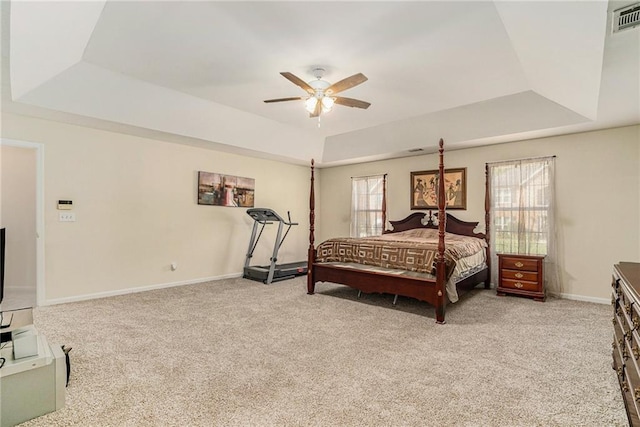 carpeted bedroom featuring a tray ceiling and ceiling fan