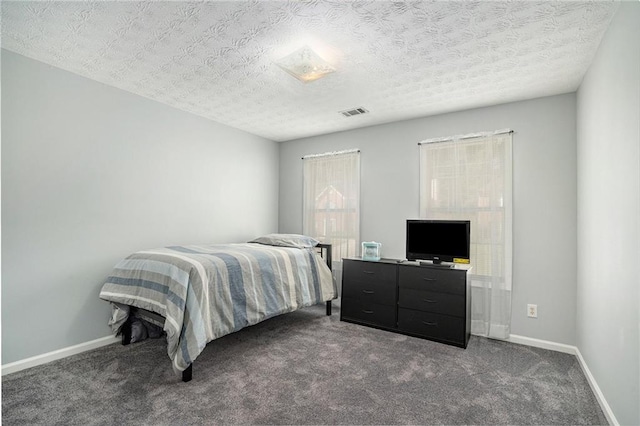 bedroom featuring dark colored carpet and a textured ceiling