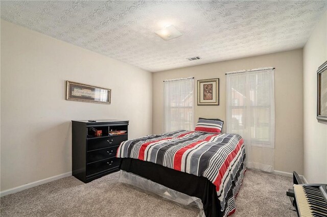 bedroom featuring light colored carpet and a textured ceiling