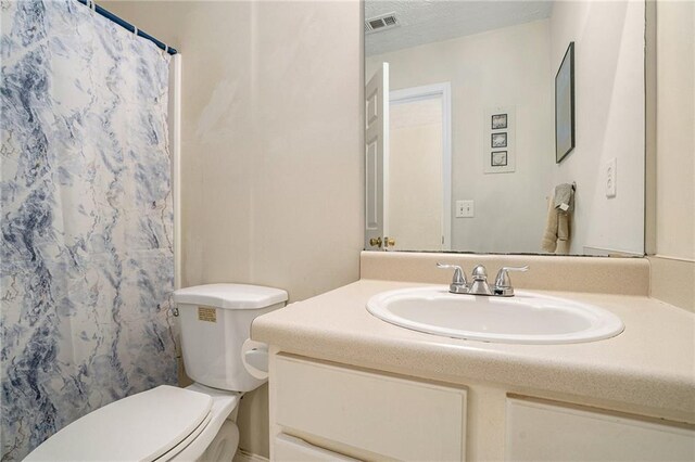 bathroom with vanity, curtained shower, toilet, and a textured ceiling