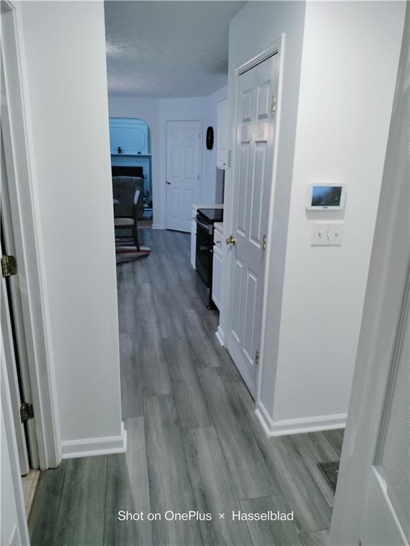 corridor with hardwood / wood-style floors and a textured ceiling