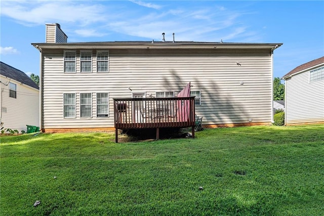 back of property featuring a wooden deck and a yard