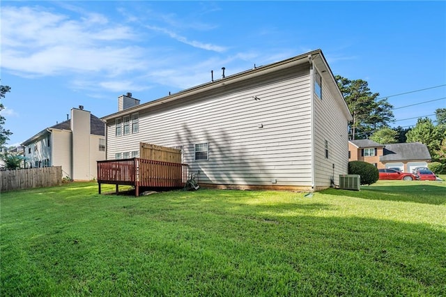 rear view of property featuring a lawn, a wooden deck, and central AC unit