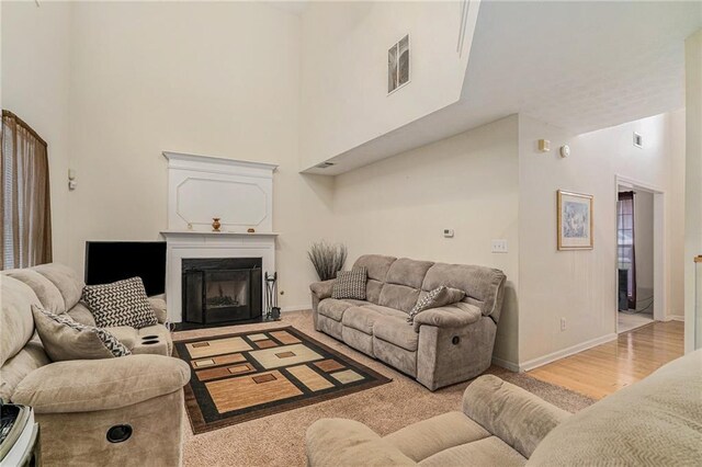 living room with light hardwood / wood-style flooring and a towering ceiling