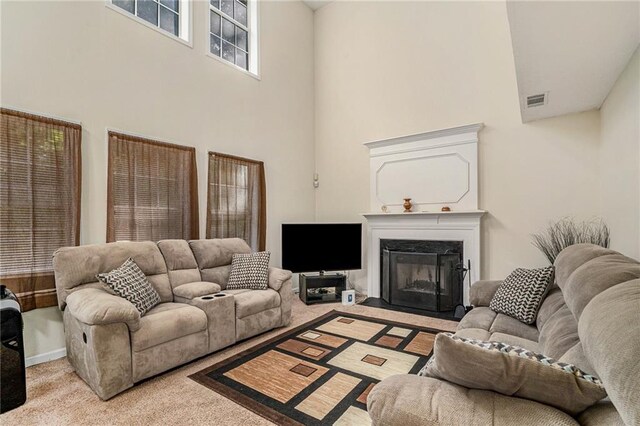 living room featuring light carpet, a high ceiling, and a premium fireplace