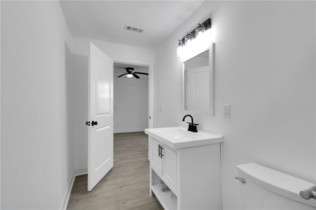 bathroom featuring wood-type flooring, vanity, toilet, and ceiling fan