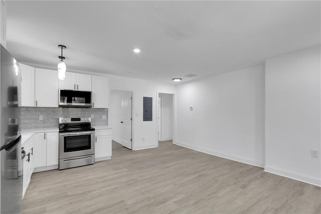 kitchen featuring white cabinets, pendant lighting, stainless steel appliances, and light hardwood / wood-style floors