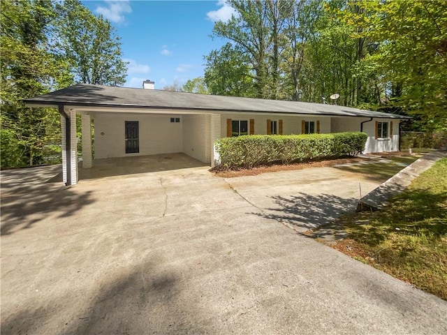 ranch-style house featuring a chimney, driveway, and an attached carport