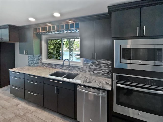 kitchen featuring backsplash, light stone countertops, stainless steel appliances, and a sink