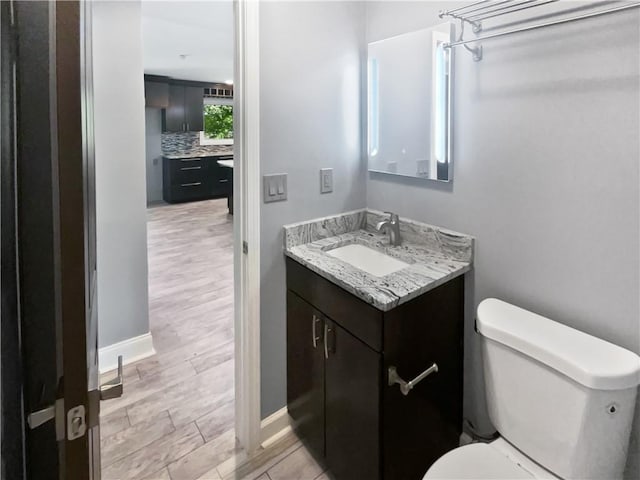 bathroom featuring baseboards, vanity, and toilet