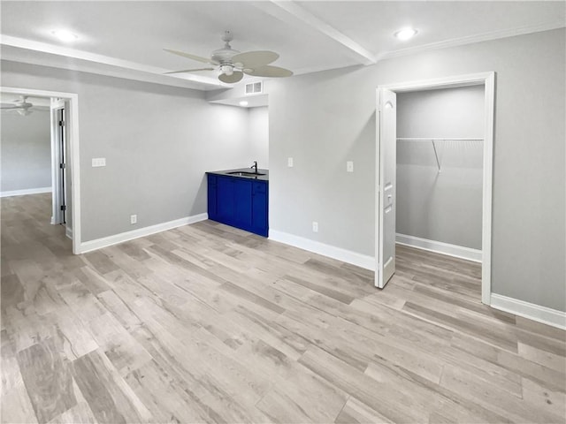 interior space with baseboards, a ceiling fan, a sink, and light wood-type flooring