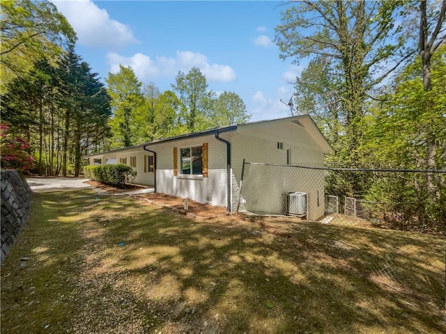 view of property exterior featuring brick siding, central air condition unit, and fence