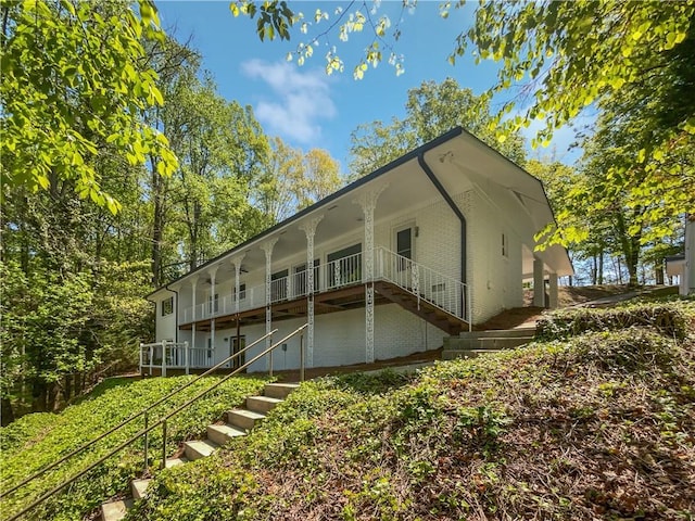 back of property featuring a ceiling fan and stairs