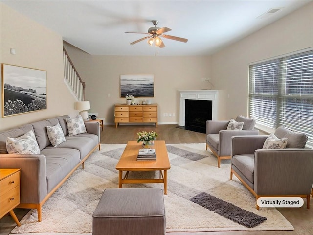 living room with wood finished floors, visible vents, baseboards, a fireplace with flush hearth, and ceiling fan