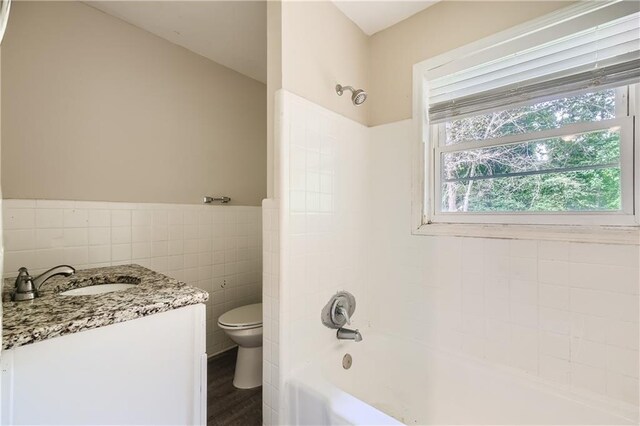 full bathroom featuring vanity, tile walls, toilet, and shower / washtub combination