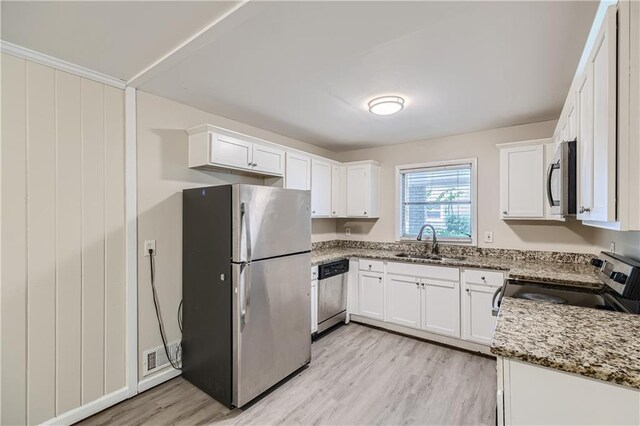 kitchen featuring white cabinets, light stone counters, appliances with stainless steel finishes, and sink