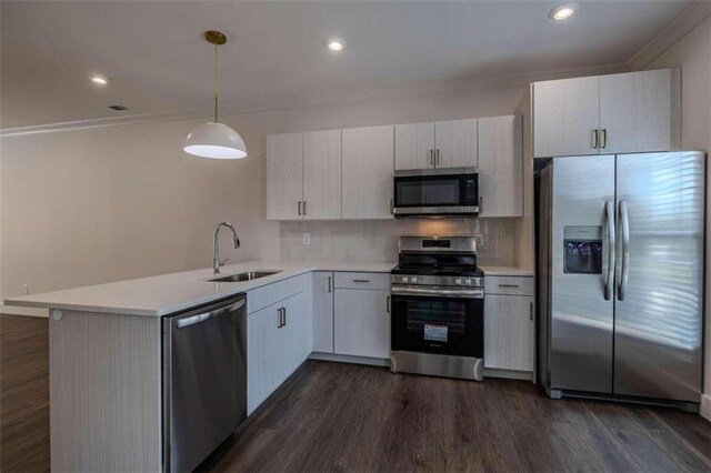 kitchen with pendant lighting, dark wood-type flooring, sink, appliances with stainless steel finishes, and kitchen peninsula