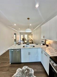 kitchen with kitchen peninsula, stainless steel appliances, sink, pendant lighting, and dark hardwood / wood-style floors