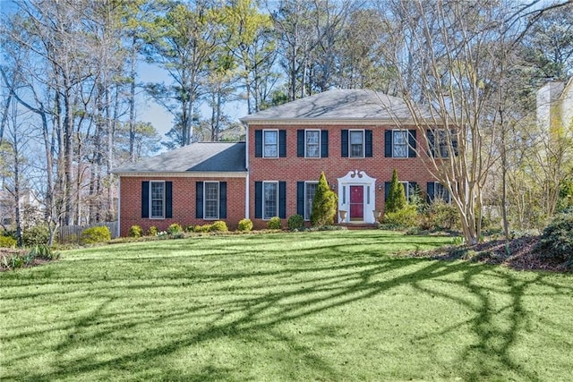 colonial inspired home with a front yard and brick siding