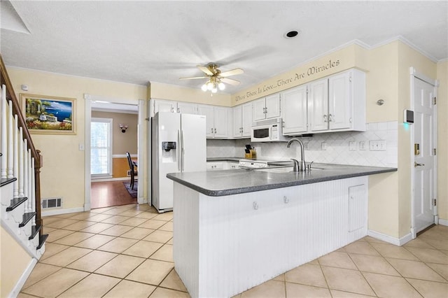 kitchen featuring white appliances, light tile patterned floors, dark countertops, and visible vents