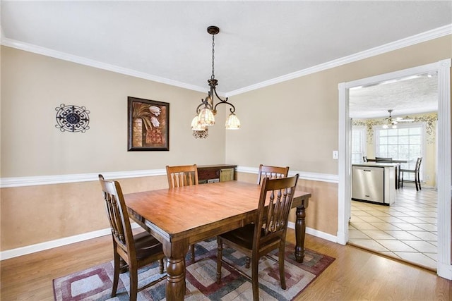 dining space with light wood-style flooring, crown molding, and baseboards