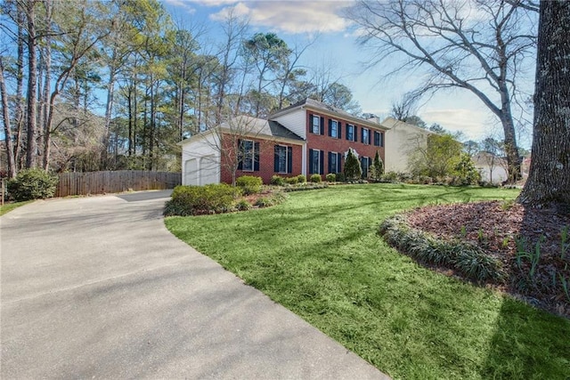 view of front of home featuring fence, concrete driveway, an attached garage, a front yard, and brick siding