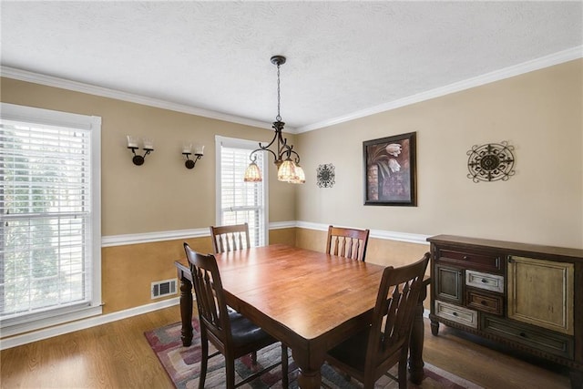 dining space with dark wood-style floors, baseboards, visible vents, a textured ceiling, and crown molding