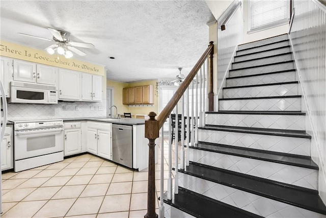 kitchen with white appliances, a ceiling fan, a peninsula, a sink, and tasteful backsplash