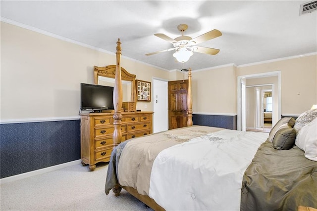 bedroom with a wainscoted wall, crown molding, light colored carpet, and visible vents