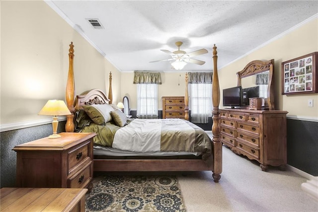 bedroom with visible vents, a textured ceiling, crown molding, light colored carpet, and ceiling fan