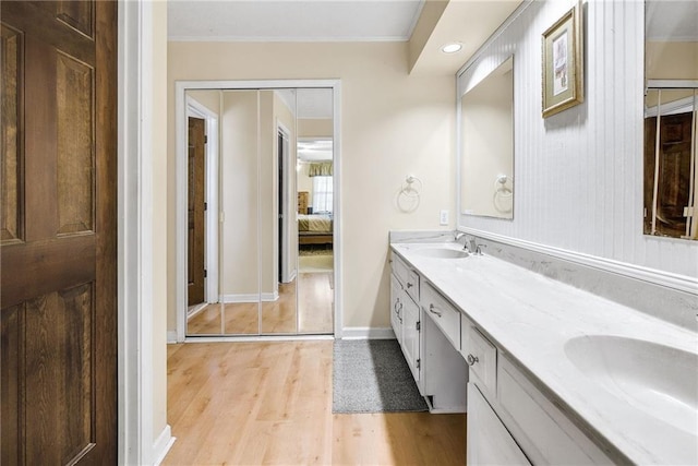 full bath featuring ensuite bath, double vanity, wood finished floors, and a sink