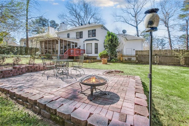 back of house with an outdoor fire pit, a chimney, a yard, a sunroom, and a patio