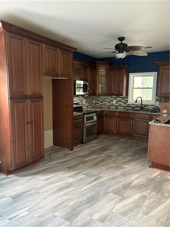 702 Moon Rd, Lawrenceville, GA 30046 - kitchen featuring stainless steel appliances, ceiling fan, tasteful backsplash, light stone counters, and glass insert cabinets