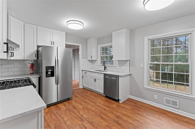 2002 Twin Falls Rd, Decatur, GA 30032 - kitchen with stainless steel appliances, backsplash, white cabinets, light stone counters, and wall chimney exhaust hood
