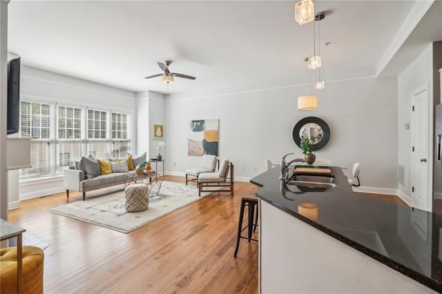 living room with light hardwood / wood-style floors, ceiling fan, and sink